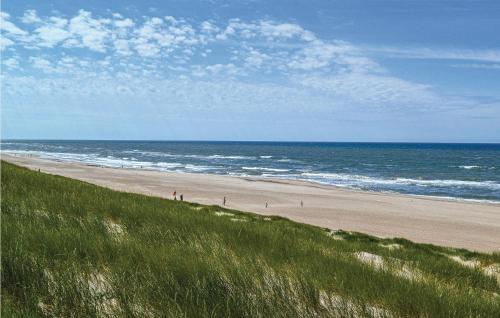 a beach with people walking on the sand and the ocean at Holiday Home Tingodden Denm I in Hvide Sande