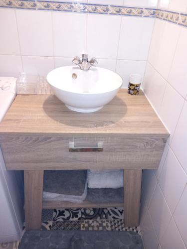 une salle de bain avec un lavabo blanc sur un comptoir en bois dans l'établissement Cosy 2, à Vias