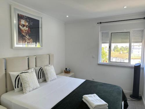 a white bedroom with a large bed and two windows at airport room in Lisbon