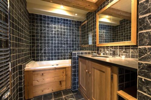 une salle de bain avec un lavabo, un miroir et une baignoire dans l'établissement L'Aquila 34 - 3-bedroom ski-in ski-out apartment, à Val dʼIsère