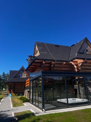 a log cabin with a black roof and windows at Domek w Białce z JACUZZI w ogrodzie in Białka Tatrzanska
