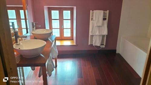 a bathroom with two sinks on a wooden floor at Logis Hôtel Château De Palaja in Carcassonne