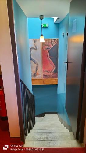 a hallway with blue walls and stairs with a painting on the wall at Logis Hôtel Château De Palaja in Carcassonne