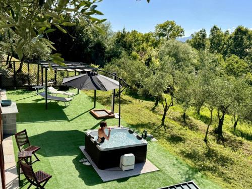 a woman sitting in a pool in a backyard at Ca' Degli Ulivi Relax - uso esclusivo con jacuzzi in Lunigiana vicino cinque terre in Agnino