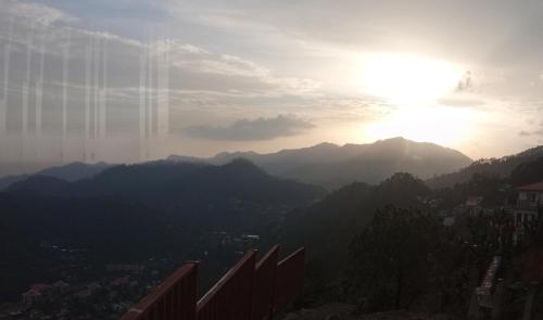 a view of the sun setting over a mountain range at Kumaon Lake's Home stay in Nainital