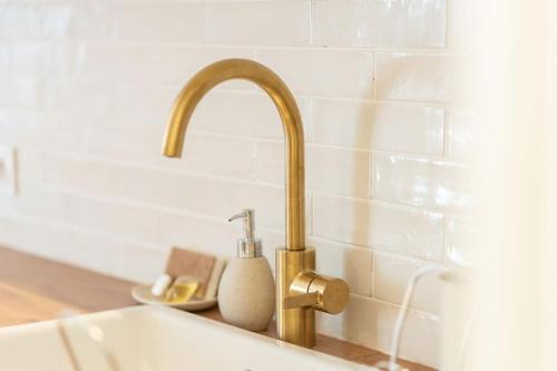 un évier de cuisine avec un robinet doré à côté d'un comptoir dans l'établissement Le Saint-Sernin Éclatant, à Toulouse