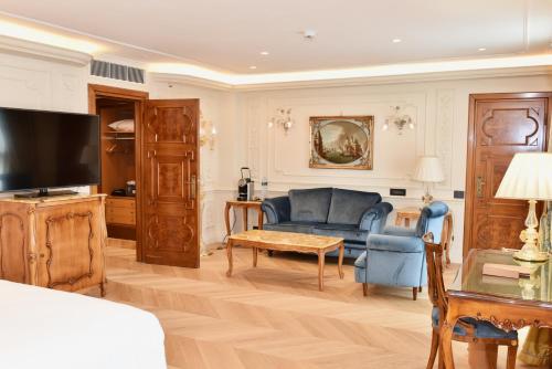 a living room with a blue couch and a tv at Parco dei Principi Grand Hotel & SPA in Rome