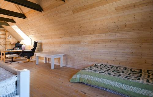 a bedroom with a wooden wall with a bed and a desk at 3 Bedroom Nice Home In Ulfborg in Ulfborg