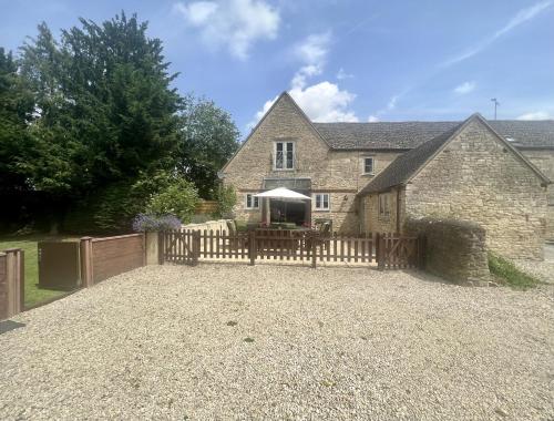 a house with a fence and a table with an umbrella at The Old Coach House in Witney