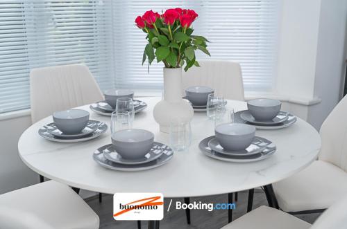 a white table with a vase with red roses on it at Three Bedroom Apartment At Buonomo Stays Short Lets & Serviced Accommodation With Netflix & Games in London