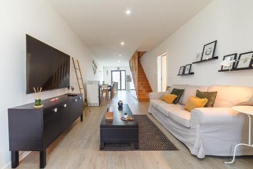 a living room with a white couch and a flat screen tv at Gafa House - Family Accommodation and Workplace in Gafanha da Nazaré