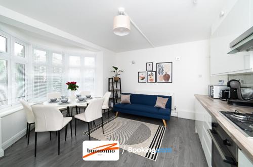 a kitchen and dining room with a table and a blue couch at Three Bedroom Apartment At Buonomo Stays Short Lets & Serviced Accommodation With Netflix & Games in London