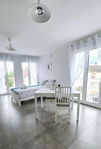 une chambre blanche avec un lit, une table et des chaises dans l'établissement Agréable studio proche Orly 