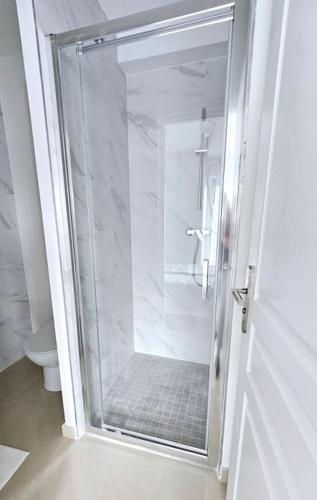 La salle de bains est pourvue d'une douche en verre et de toilettes. dans l'établissement Agréable studio proche Orly 