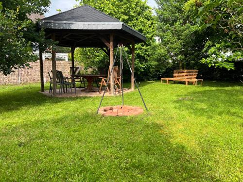 a gazebo with a table and a bench in the grass at Kurpark Ferienwohnung in Schleiden