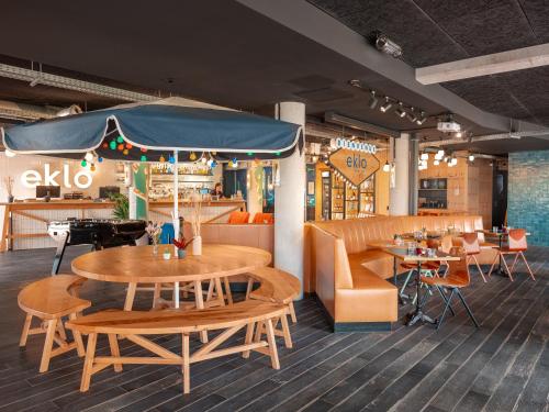 un restaurant avec des tables et des chaises en bois ainsi qu'une table et des chaises dans l'établissement Eklo Paris Roissy CDG Airport, à Roissy-en-France