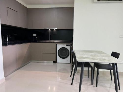 a kitchen with a table and a washing machine at The PeAk Residence, Multi-Apartment by Emma in Phnom Penh