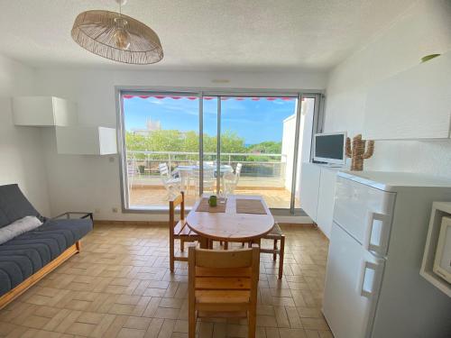 - une cuisine et une salle à manger avec une table et un canapé dans l'établissement Pacific 1-Studio cabine, vue mer, parking, à La Grande Motte