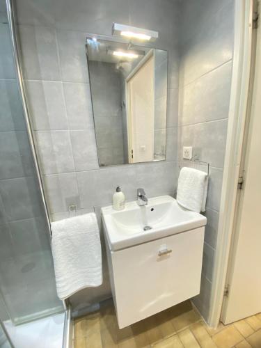 une salle de bain blanche avec un lavabo et un miroir dans l'établissement Pacific 1-Studio cabine, vue mer, parking, à La Grande Motte