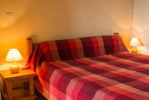 a bed with a plaid blanket and two lamps at Gites de france a brion in Brion