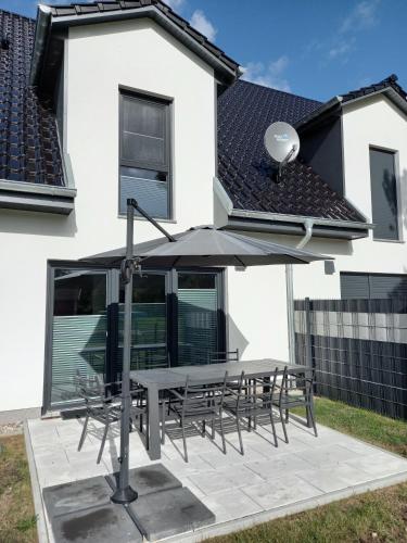 a table and chairs with an umbrella in front of a house at Boddenblick 9 a in Fuhlendorf