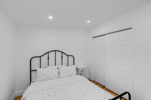 a white bedroom with a black bed with white pillows at CityScape in Chelsea