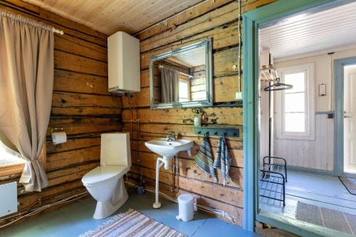 a bathroom with wooden walls and a toilet and a sink at Myllytupa in Merikaarto