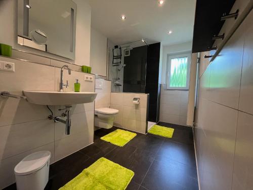 a bathroom with a sink and a toilet and yellow rugs at Astrid's Appartements in Winterberg