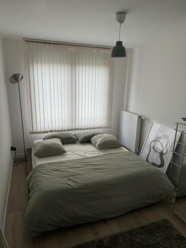 un lit dans une chambre avec une grande fenêtre dans l'établissement Appartement Cosy, proche Stade de France, à Saint-Denis