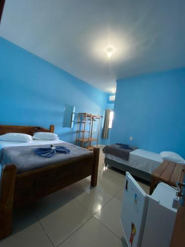 a blue room with two beds and a refrigerator at Hotel Jardins in Porto Velho
