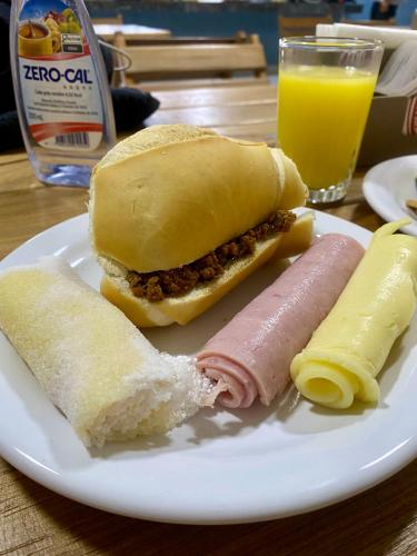 een broodje op een bord naast een glas sinaasappelsap bij Hotel Jardins in Porto Velho