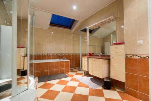 une salle de bain avec une baignoire, un lavabo et un miroir dans l'établissement Maison familiale au calme proche de Paris, à Franconville