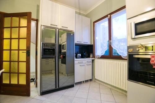  La cuisine est équipée de placards blancs et d'un réfrigérateur. dans l'établissement Maison familiale au calme proche de Paris, à Franconville