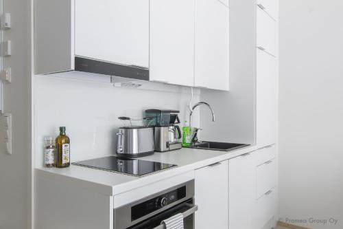 une cuisine avec des armoires blanches et un four à plaques de cuisson dans l'établissement Pramea Apartments Holvi, à Kuopio