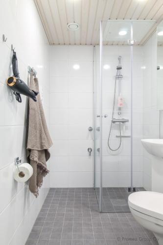 a white bathroom with a shower and a toilet at Pramea Apartments Holvi in Kuopio