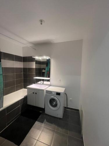 une salle de bain avec une machine à laver et un lavabo dans l'établissement Appartement à Paris, à Vigneux-sur-Seine