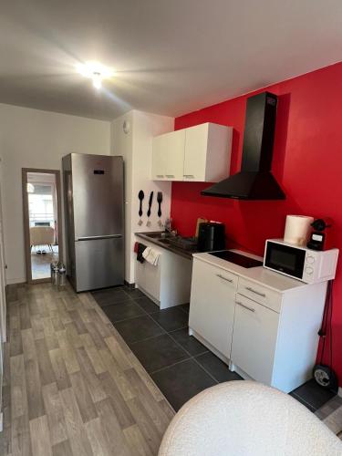 une cuisine avec des murs rouges et des armoires blanches et un réfrigérateur dans l'établissement Appartement à Paris, à Vigneux-sur-Seine