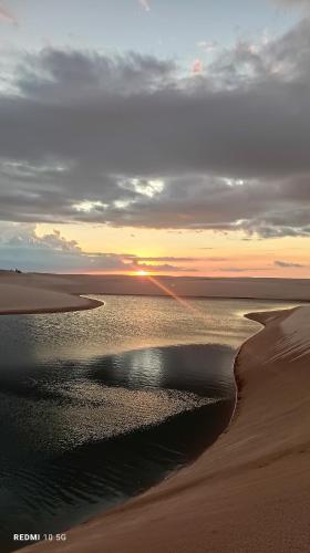a beach with the sun setting in the horizon at Quartinho Branco in Atins