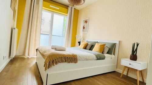 une chambre avec un lit aux murs jaunes et une fenêtre dans l'établissement Riviera Suite - Spacieux T3 - 5 min du métro- Paris centre à 10min, à Asnières-sur-Seine