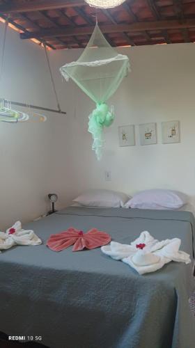 a bed with three towels on top of it at Quartinho Branco in Atins