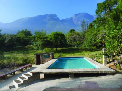 a swimming pool with mountains in the background at Jungle Hut in Masinagudi