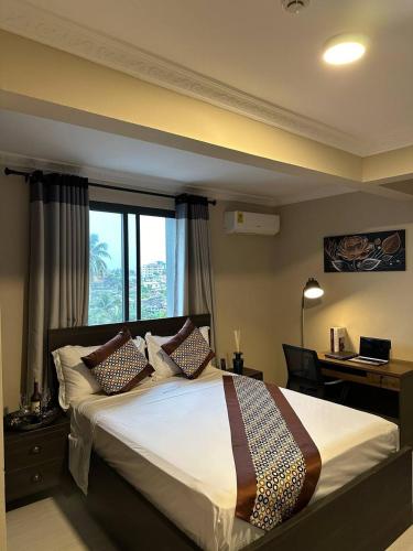 a bedroom with a bed with a desk and a window at Mansah Plus Hotel and Apartments in Accra