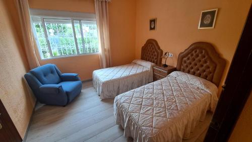 sypialnia z 2 łóżkami i niebieskim krzesłem w obiekcie Sevilla, Casa Rural Villa Amalia w mieście Alcalá de Guadaira