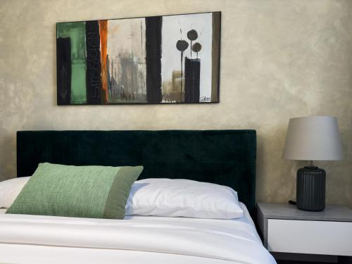 a bed with a green pillow and a picture on the wall at Istria Symphony Apartment in Labin