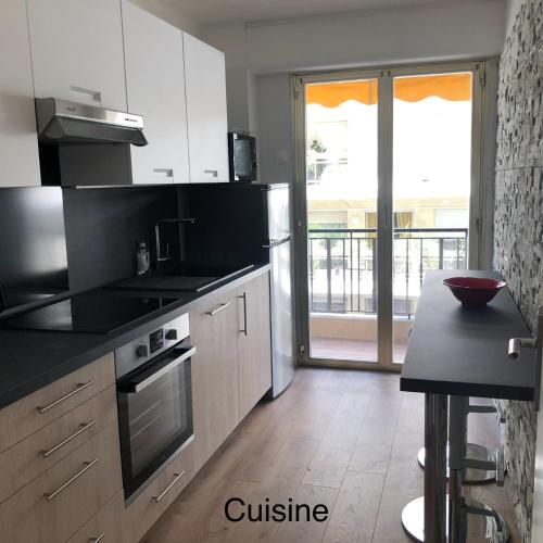 une cuisine avec des armoires blanches et un comptoir noir dans l'établissement CARRE D'OR - Appartement 3P - Antibes Centre - Carré d'Or, à Antibes