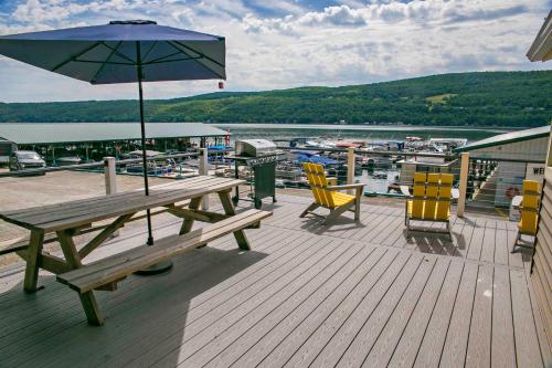 a wooden deck with a picnic table and chairs and an umbrella at The Mooring in Hammondsport