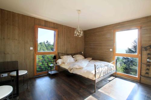 1 dormitorio con 1 cama con paredes y ventanas de madera en Chalet luxe 13 personnes SPA SAUNA VOSGES-GERARDMER, en Le Tholy