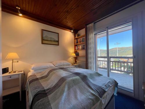 a bedroom with a bed and a large window at Homency - Résidence de l'Alpe 23 in L'Alpe-d'Huez
