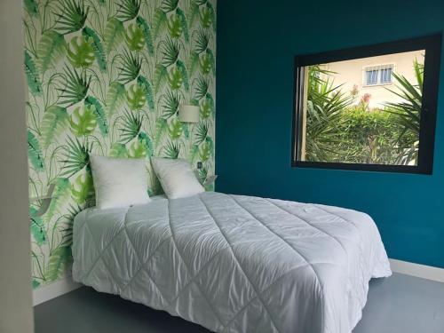 - une chambre avec un lit et un papier peint à feuilles dans l'établissement Villa Ronsard - vue mer, à Fréjus