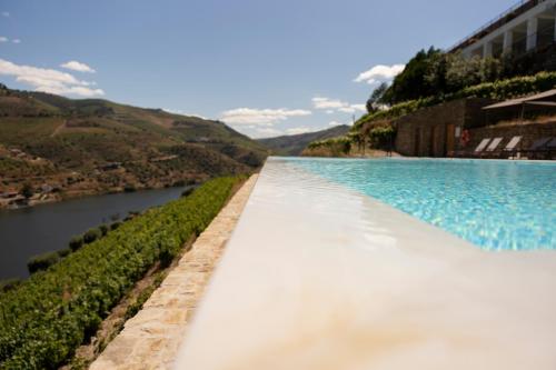 a infinity pool with a river in the background at Quinta São Luiz The Vine House Douro in Tabuaço